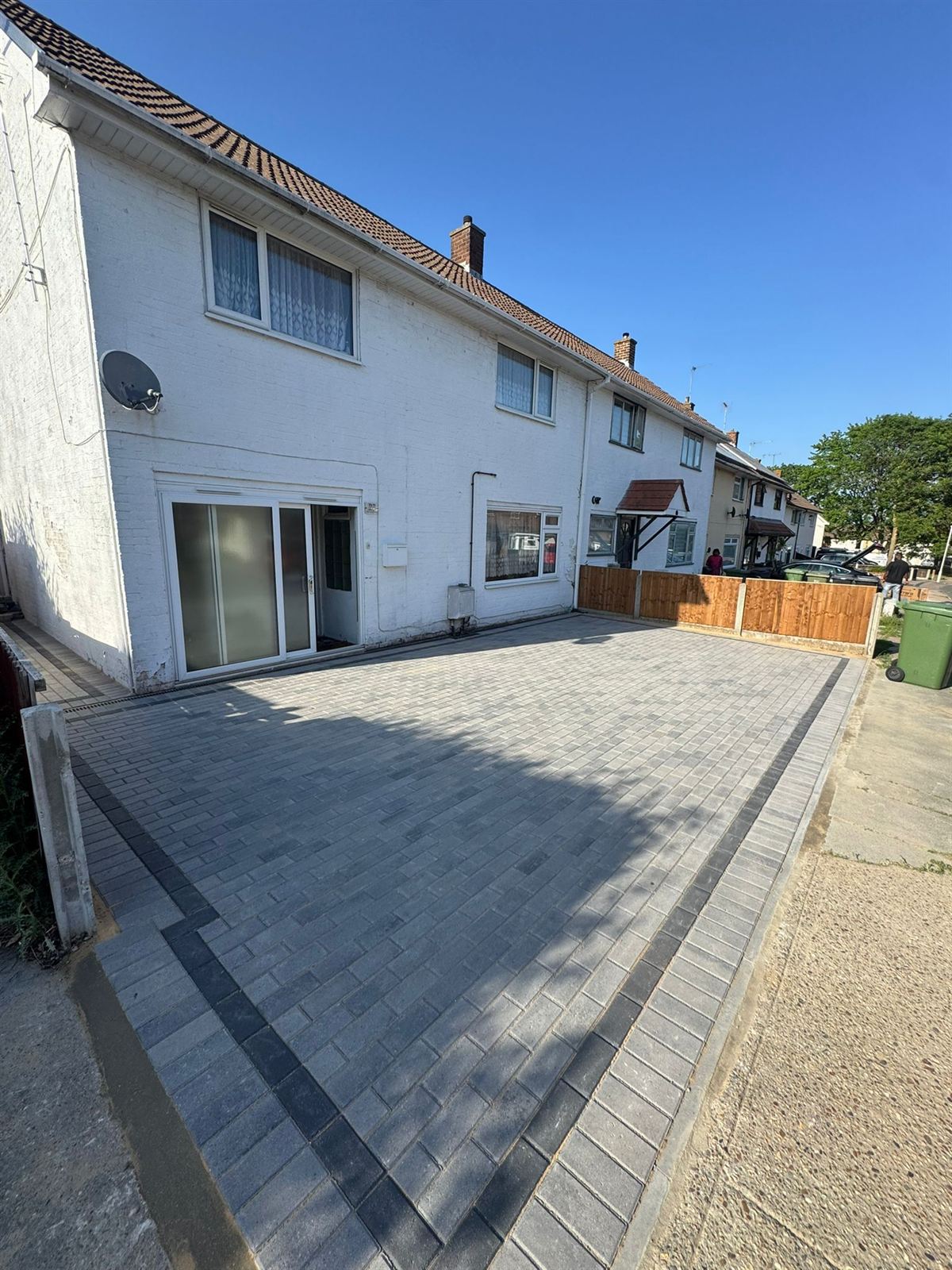 Block paving driveway leading to a white rendered house