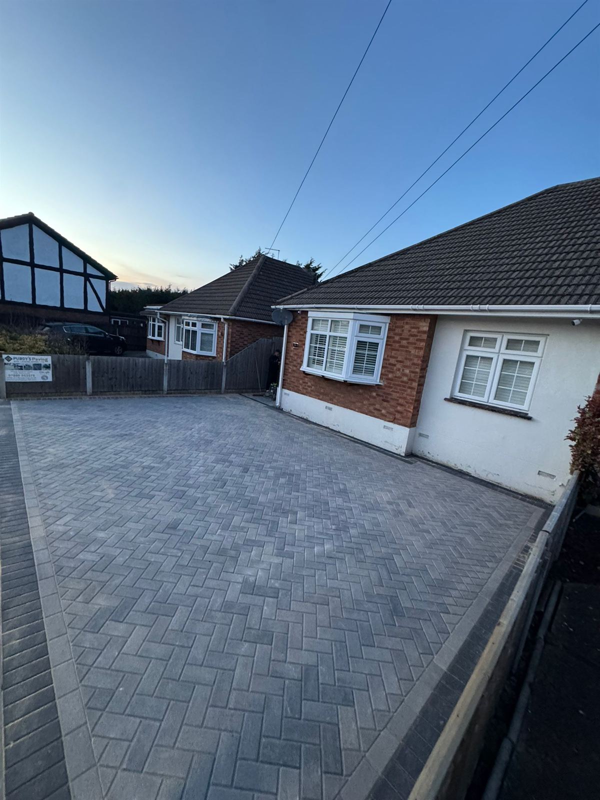 Block paving driveway at a bungalow under a clear blue sky